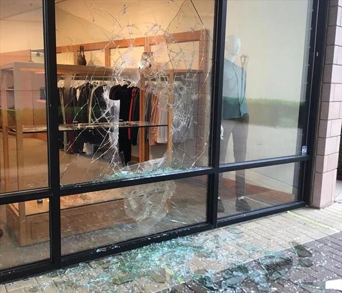 Store front was vandalized and has a broken out window with glass scattered on the entrance sidewalk