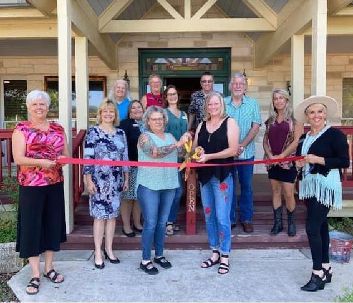 group photo of Wimberley Chamber of Commerce members holding a ribbon to cut during the ceremony