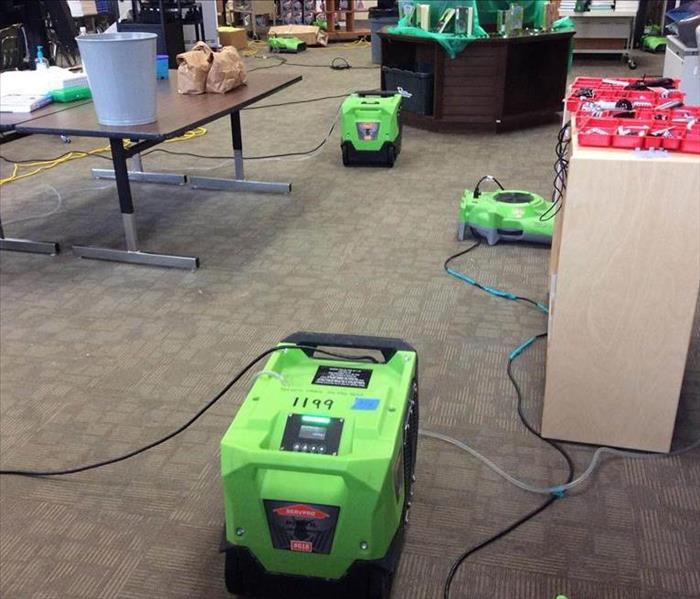 Dehumidifiers, air movers and other drying equipment set up in a library to dry the major water damaged areas