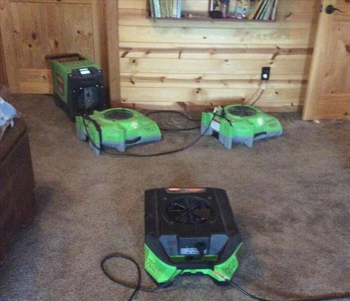 cabin room with wet carpets and green high powered air movers set out drying the area